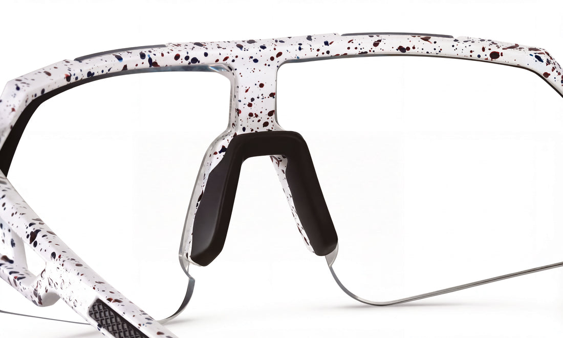 Close-up of white speckled cycling sunglasses frame with black nose pads, no lenses
